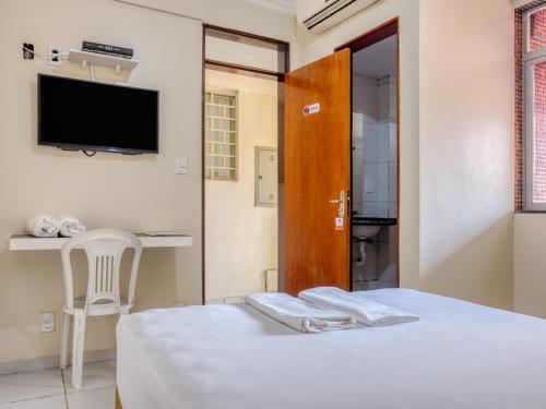 um quarto com uma cama, uma televisão e uma cadeira em Pousada Ilha Costeira em São Luís