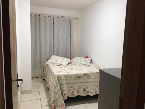 een kleine slaapkamer met een bed en een raam bij Suíte e Quarto em apartamento familiar, Praia do Morro! in Guarapari