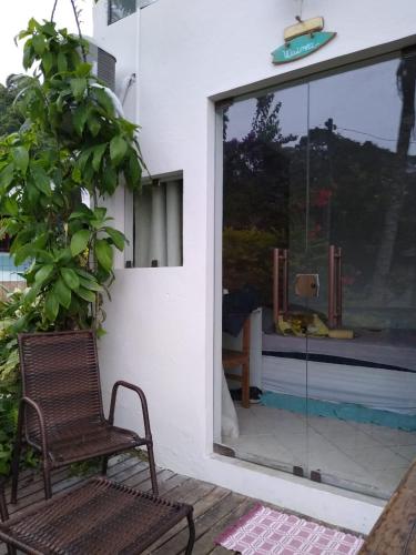 a chair next to a window with a swimming pool at Haleiwa chalés e suítes - A Guest House do Prumirim in Ubatuba