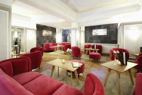 a waiting room with red chairs and tables at Schlosshotel Lacknerhof in Flachau