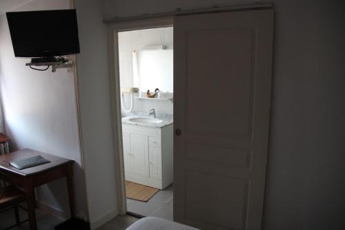 - une porte ouverte donnant sur une salle de bains avec lavabo dans l'établissement Hostellerie du Beffroy, à Besse-et-Saint-Anastaise