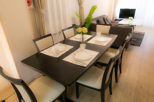 a dining room table and chairs with a black table and flowers at Nao's Guesthouse 2 一軒家貸切 in Osaka
