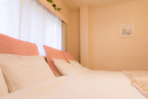 a white bed with white pillows and a window at Nao's Guesthouse 2 一軒家貸切 in Osaka