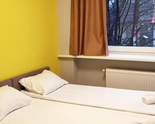 two beds in a room with a window at Bridge Hotel in Rīga
