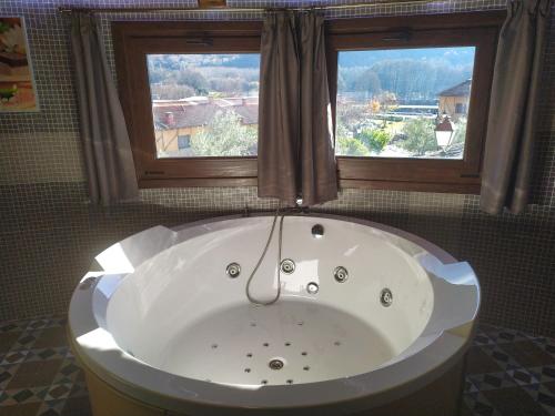 a bath tub in a bathroom with two windows at Complejo Rural Los Chozos Valle del Jerte in Jerte