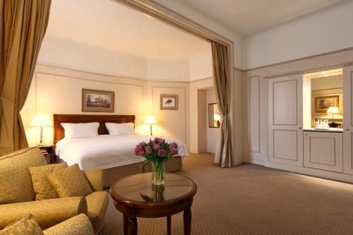 ブリュッセルにあるホテル ル プラザ ブリュッセルのベッド、ソファ、テーブルが備わるホテルルームです。
