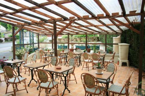 a patio with tables and chairs under a wooden pergola at Auberge Saint Martin in Saint-Martin-Terressus