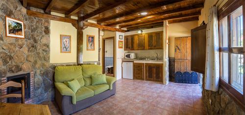 a living room with a couch and a kitchen at Complejo Rural Los Chozos Valle del Jerte in Jerte