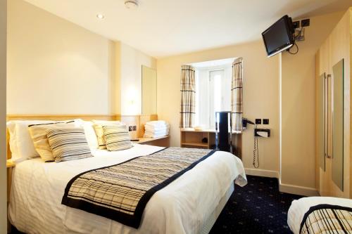um quarto de hotel com uma cama e uma televisão em Queens Mansions: Lakeland Suite em Blackpool