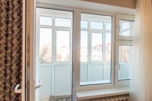Zimmer mit Glastüren und Fenster in der Unterkunft Avangard Aparts - Avangard in Atyrau