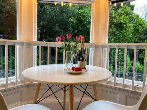 a table with a bottle of wine and flowers on a balcony at Biskey Howe flat - FREE off-site Health Club access with Pool, Sauna, Steam Room & Gym in Windermere