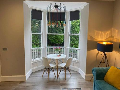 a living room with a table and chairs and a window at Biskey Howe flat - FREE off-site Health Club access with Pool, Sauna, Steam Room & Gym in Windermere