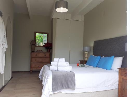 a bedroom with a large white bed with blue pillows at Whales Way Ocean Retreat in Wilderness