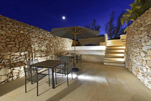 a patio with a table and chairs and a stone wall at Villa Pirreca in Favignana
