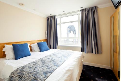 a bedroom with a bed with blue pillows and a window at Queens Mansions: Ocean View Apartment in Blackpool