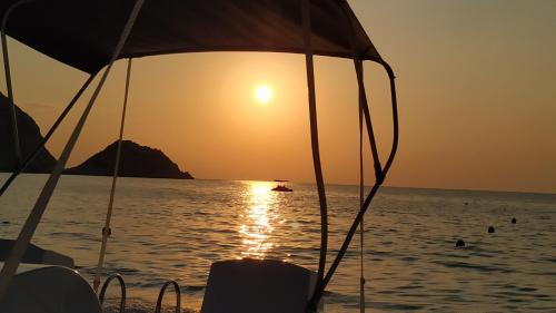a sunset on the beach with a boat in the water at Ioannis House Sea View-Perfect family holidays in Lourdhata