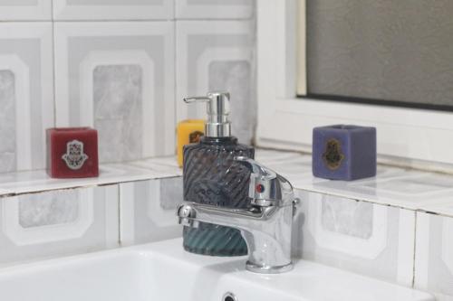un lavandino del bagno con un distributore di sapone sopra di Tufina Hostel a Tirana