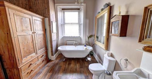 a bathroom with a tub and a toilet and a sink at Ascot House Hotel in Torquay