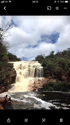 a man in the water in front of a waterfall at Casa Verde na Chapada Diamantina in Palmeiras
