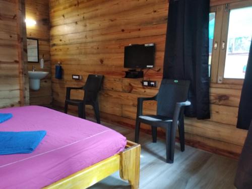 a bedroom with a bed and two chairs and a tv at Samsun Pride in Chaoka