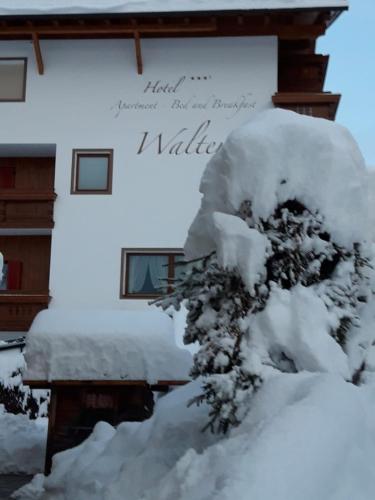 a snow covered tree in front of a building at Hotel Garni Walter in Ortisei