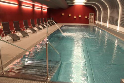 a large indoor swimming pool with chairs in a building at Le Mirabeau Resort & Spa in Zermatt