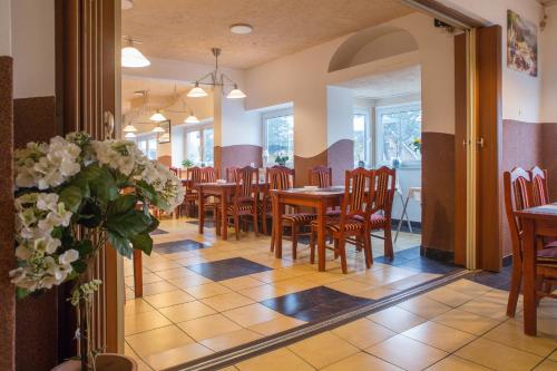 een eetkamer met tafels, stoelen en bloemen bij Hotel Nordig in Flensburg