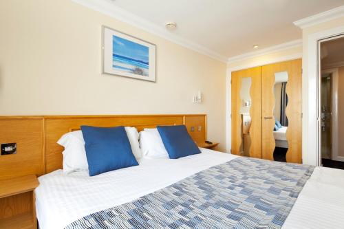 - une chambre avec un grand lit et des oreillers bleus dans l'établissement Queens Mansions: Sunset Apartment, à Blackpool