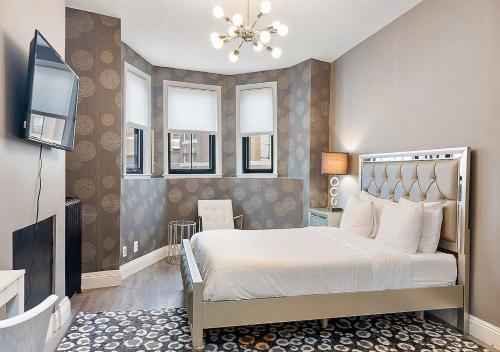 1 dormitorio con 1 cama, TV y ventanas en Suites At 143 Arlington Street en Boston