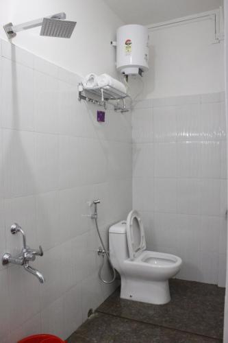 a white bathroom with a toilet and a light at Aisha Guest House Bed & Breakfast in Cherrapunji