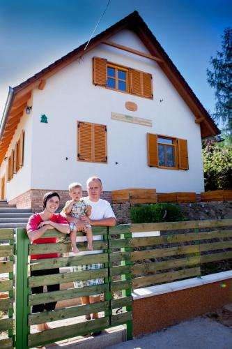a family standing on a fence in front of a house at Rozmaring Vendégház in Zengővárkony