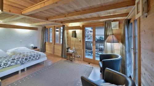 a bedroom with a bed and chairs and a window at Hotel Restaurant Les Lilas in Les Diablerets