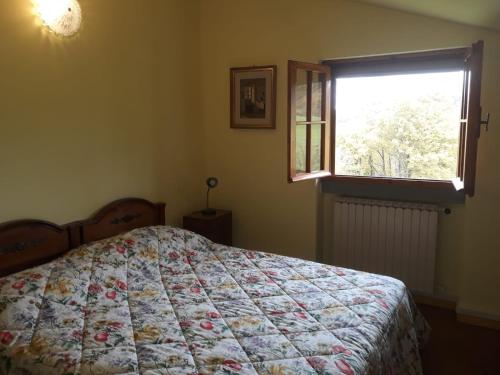 a bedroom with a bed with a quilt and a window at App.to Pian del Ronco in Pellegrino Parmense