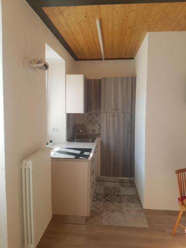 a kitchen with white cabinets and a wooden ceiling at Domus Alba Lenno in Lenno