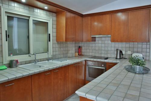 una cocina con armarios de madera y electrodomésticos de acero inoxidable en Nestor Hillside House by TrulyCyprus en Moniatis