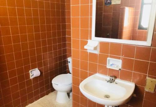 uma casa de banho com um WC, um lavatório e um espelho. em Hotel El Kiosco em Acapulco