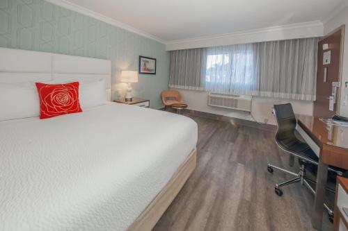 a hotel room with a large bed and a desk at Pasadena Rose & Crown Hotel in Pasadena