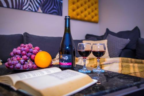 una mesa con dos copas de vino y un libro en ORNAVA Boutique Apartments, en Ternopilʼ