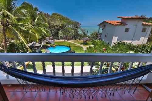 a hammock on a balcony with a view of a pool at Pousada Enseada Dos Golfinhos in Pipa