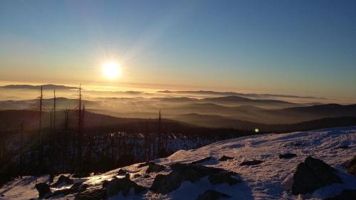 a view of the sun setting on a snowy mountain at Hotel Dreisonnenberg in Neuschönau