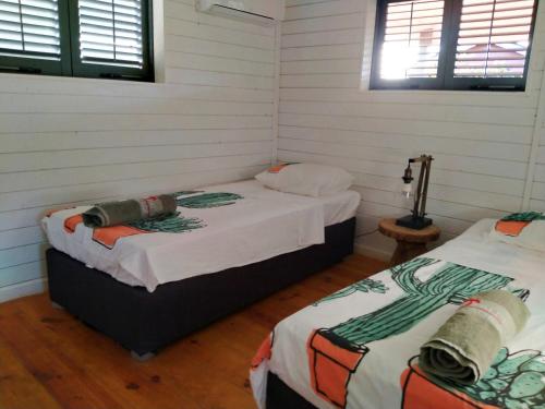 two beds in a room with white walls at Red Palm Village in Kralendijk
