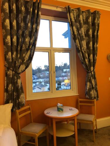 a bedroom with a window and a table and chairs at The Purple Tree Guest House in Torquay