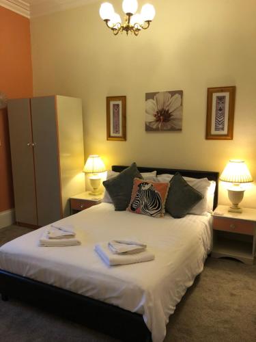 a bedroom with a bed with two lamps and towels on it at The Purple Tree Guest House in Torquay