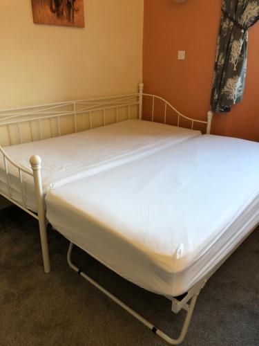 two beds in a room with white sheets at The Purple Tree Guest House in Torquay