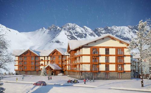a large building with snow covered mountains in the background at New Gudauri Apartment Belle Epoque With a Terrace in Gudauri