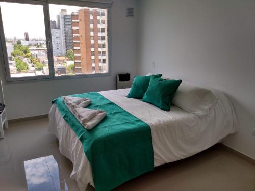 Un dormitorio con una cama con almohadas verdes y una ventana en Buena Vista Bahía en Bahía Blanca