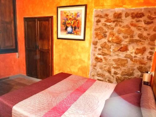 1 dormitorio con cama y pared de piedra en Casa con jacuzzi la olivera, en Chert