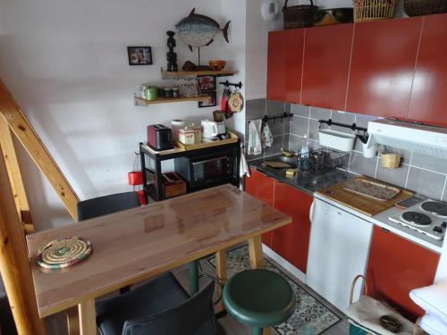 małą kuchnię z czerwonymi szafkami i drewnianym stołem w obiekcie STUDIO Prapoutel w mieście Prapoutel