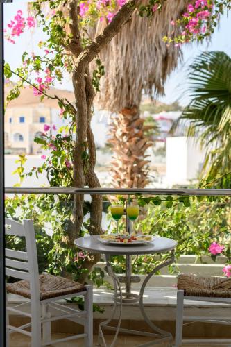 a table and chairs on a balcony with a tree at Alesahne Beach Hotel in Kamari