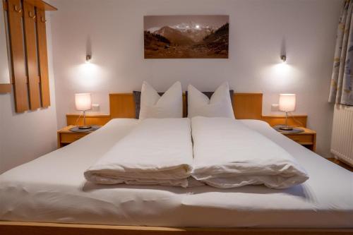 a large white bed in a bedroom with two lamps at Zöschgenhof in Matrei in Osttirol